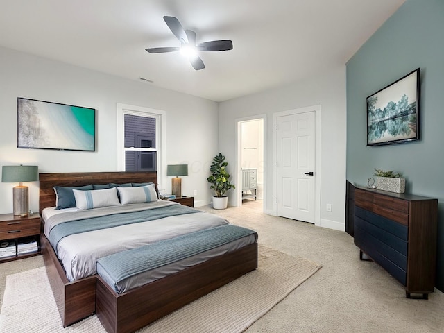 bedroom with connected bathroom, light colored carpet, and ceiling fan