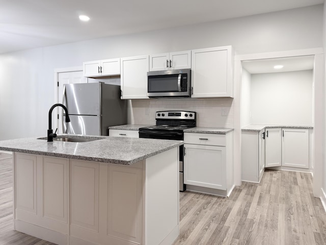 kitchen featuring backsplash, stainless steel appliances, a kitchen island with sink, and white cabinets