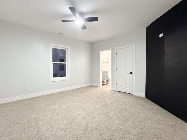 unfurnished bedroom featuring ensuite bath, light colored carpet, and ceiling fan