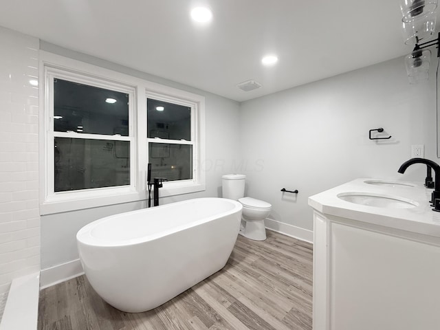 full bathroom with hardwood / wood-style flooring, shower with separate bathtub, vanity, and toilet