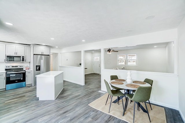 kitchen with appliances with stainless steel finishes, a center island, light hardwood / wood-style floors, and ceiling fan