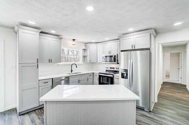 kitchen featuring appliances with stainless steel finishes, a center island, light hardwood / wood-style flooring, and sink