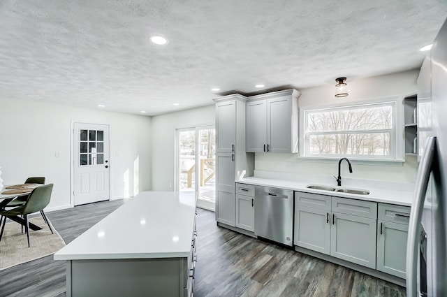 kitchen with sink, a center island, dark wood-type flooring, gray cabinets, and appliances with stainless steel finishes