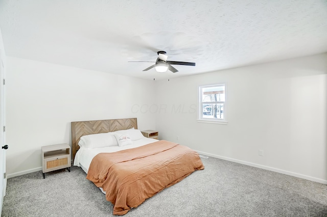 bedroom with ceiling fan, light colored carpet, and a textured ceiling