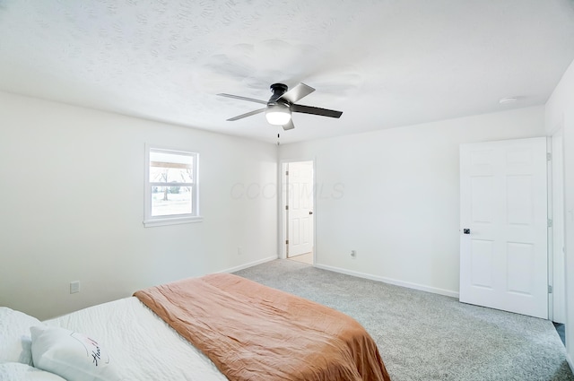 carpeted bedroom with ceiling fan and a textured ceiling