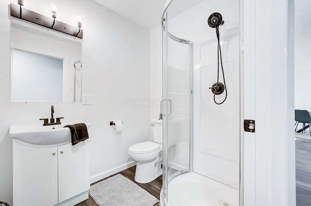 bathroom with hardwood / wood-style floors, vanity, an enclosed shower, and toilet