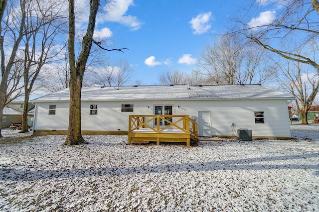 snow covered house featuring central AC unit and a deck