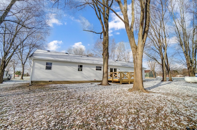 snow covered rear of property with a deck