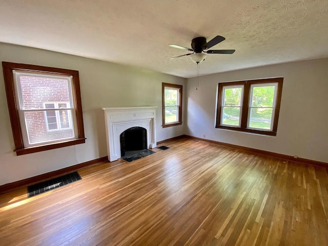 unfurnished living room featuring ceiling fan, light hardwood / wood-style floors, and a textured ceiling