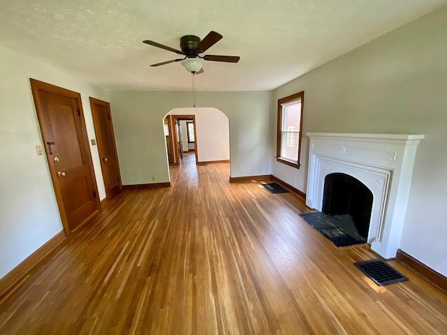 unfurnished living room featuring a textured ceiling, dark hardwood / wood-style floors, and ceiling fan