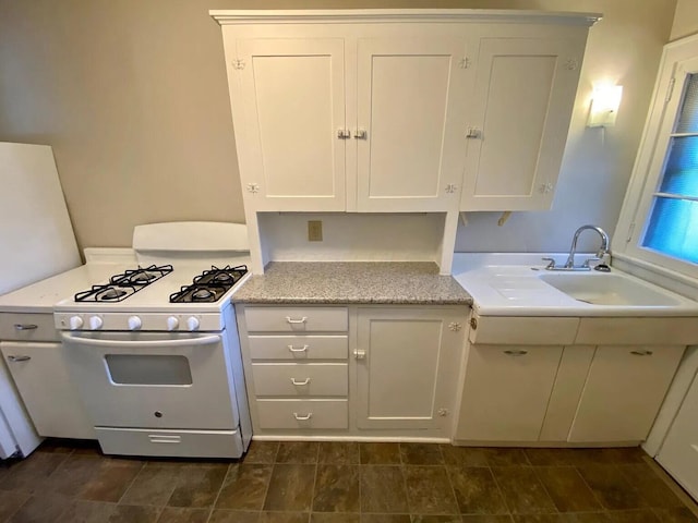 kitchen featuring white cabinets, white gas range oven, and sink