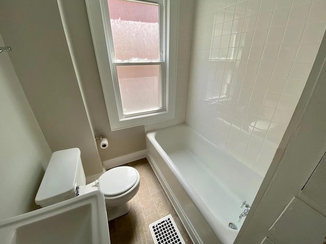 bathroom featuring tile patterned floors, a washtub, and toilet