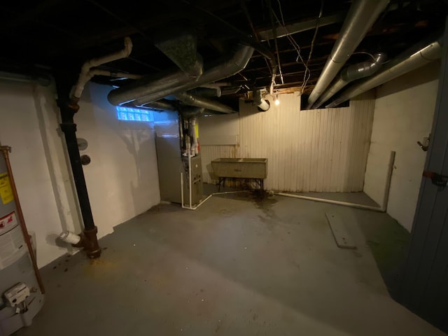 basement featuring heating unit, sink, and water heater