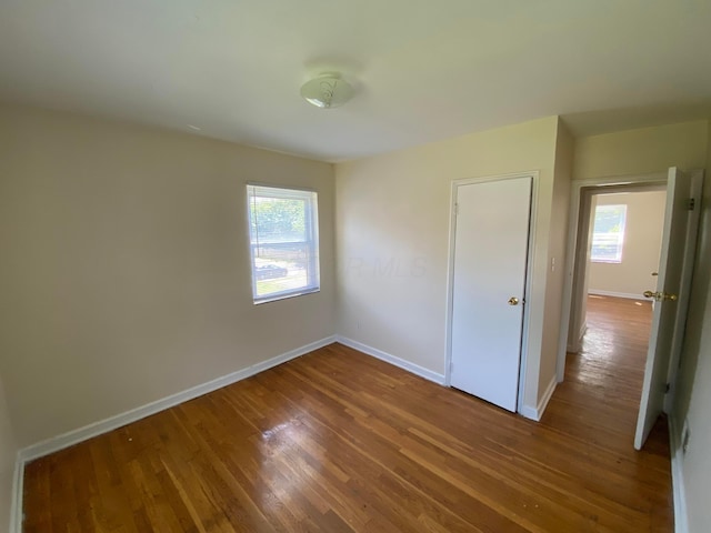 unfurnished bedroom featuring hardwood / wood-style flooring and multiple windows