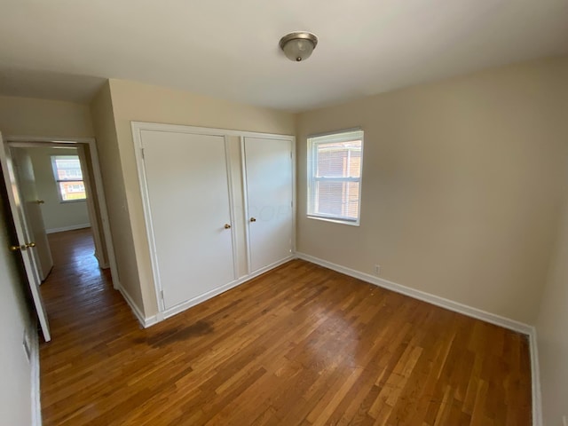 unfurnished bedroom with wood-type flooring and multiple windows