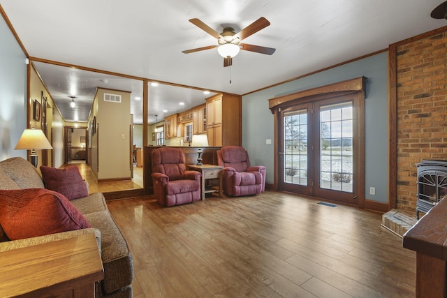 living area with crown molding, visible vents, and wood finished floors