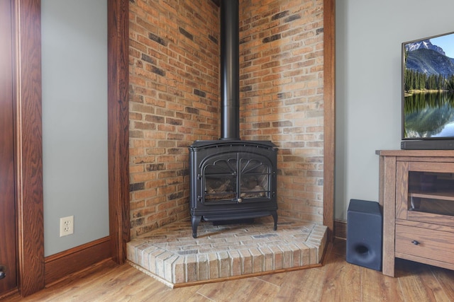 details with a wood stove, baseboards, and wood finished floors