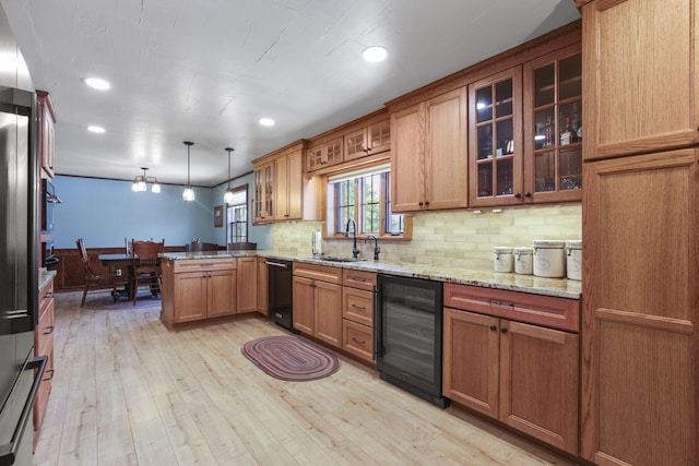 kitchen with wine cooler, brown cabinets, light wood-style flooring, a sink, and a peninsula