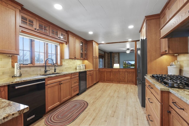 kitchen with black appliances, premium range hood, brown cabinets, and a sink