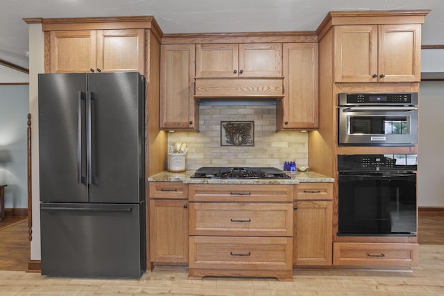 kitchen with tasteful backsplash, baseboards, light stone countertops, light wood-type flooring, and black appliances