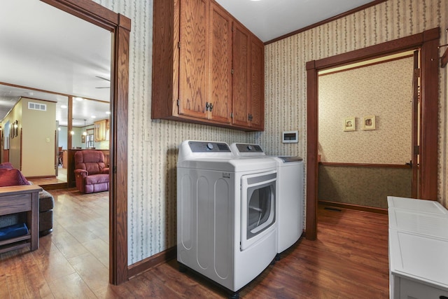 clothes washing area with wallpapered walls, cabinet space, visible vents, dark wood-type flooring, and washer and dryer