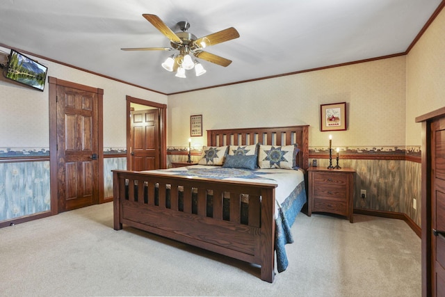 carpeted bedroom with a wainscoted wall, a ceiling fan, ornamental molding, and wallpapered walls