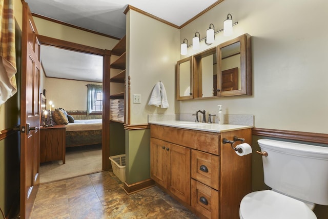 ensuite bathroom with toilet, stone finish floor, ensuite bathroom, crown molding, and vanity