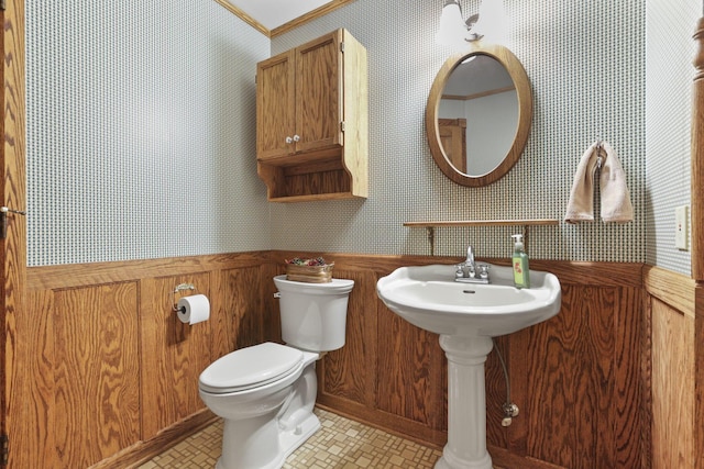 bathroom with wainscoting, a sink, toilet, and wallpapered walls