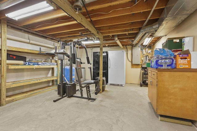 unfinished basement featuring freestanding refrigerator and electric panel