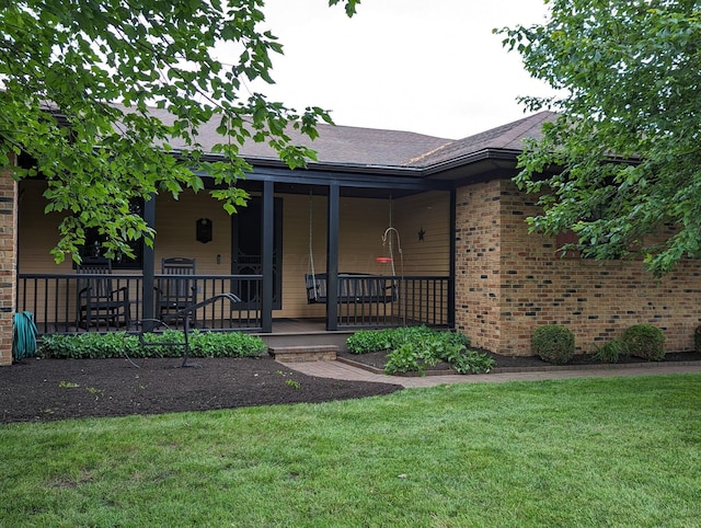 view of front of home with covered porch, brick siding, and a front lawn