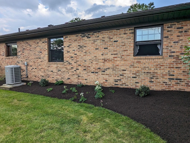 view of home's exterior with central AC, brick siding, and a lawn