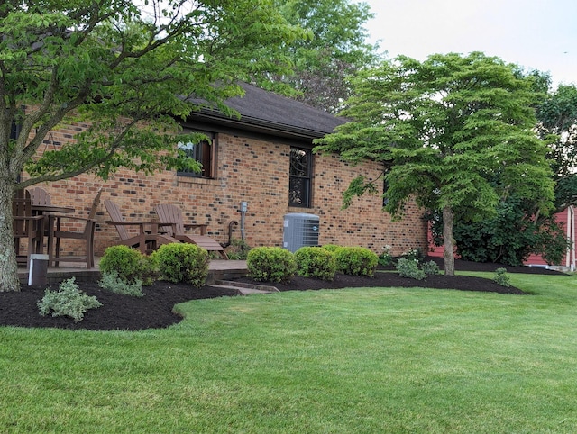 view of front of home with a front lawn, brick siding, and central air condition unit