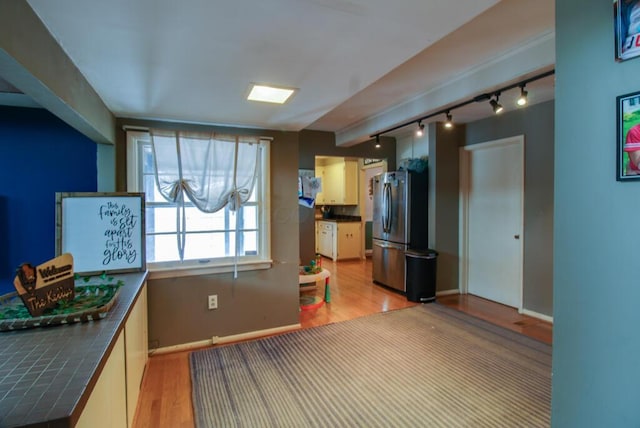 kitchen featuring tile counters, light hardwood / wood-style floors, stainless steel refrigerator, and track lighting