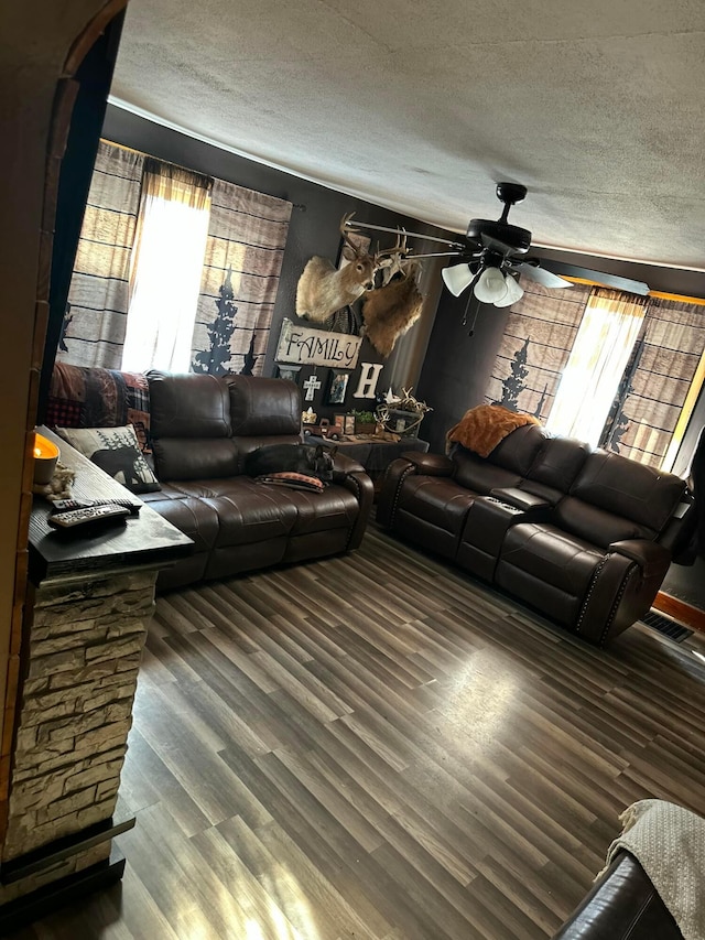 living room featuring a textured ceiling, ceiling fan, and dark hardwood / wood-style flooring