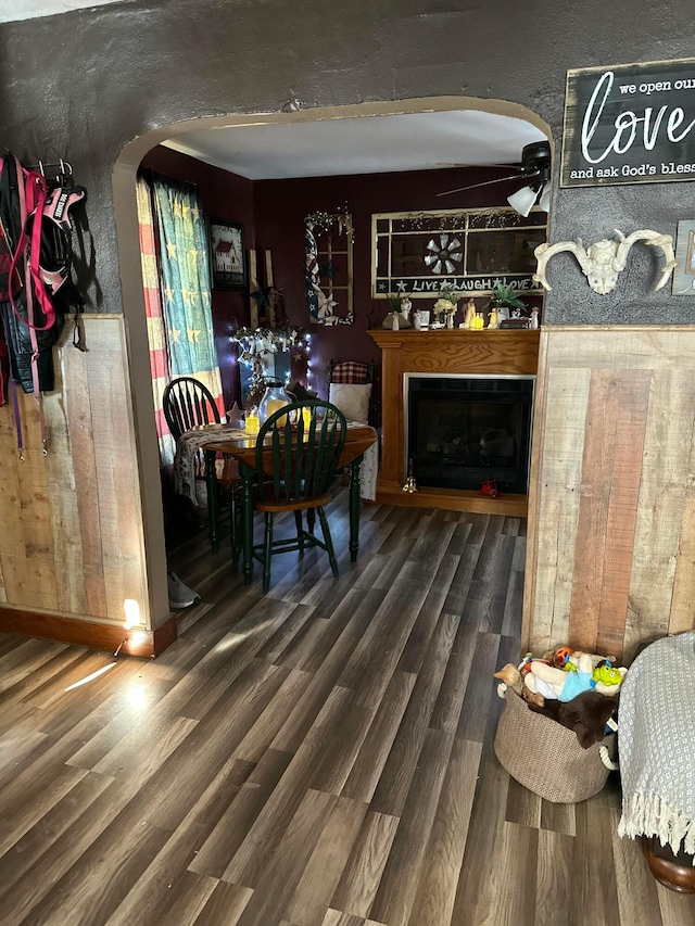 bar with a fireplace, wood finished floors, arched walkways, and ceiling fan