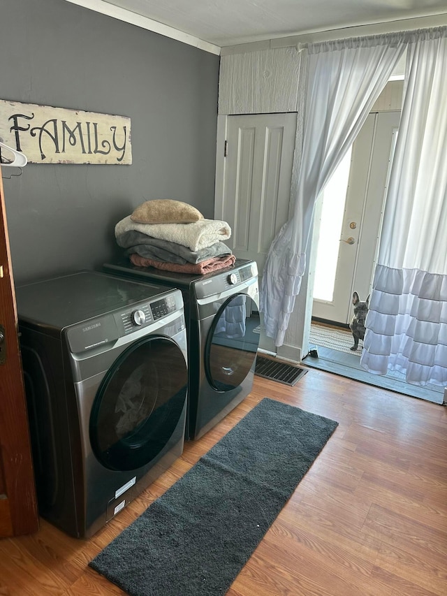 laundry room with laundry area, wood finished floors, crown molding, and separate washer and dryer