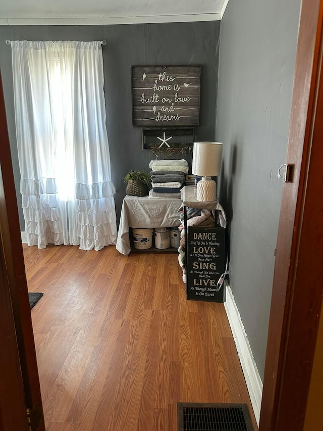 bedroom with wood finished floors, visible vents, and baseboards