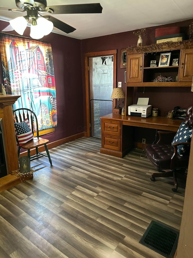 office area with visible vents, a ceiling fan, wood finished floors, and built in desk