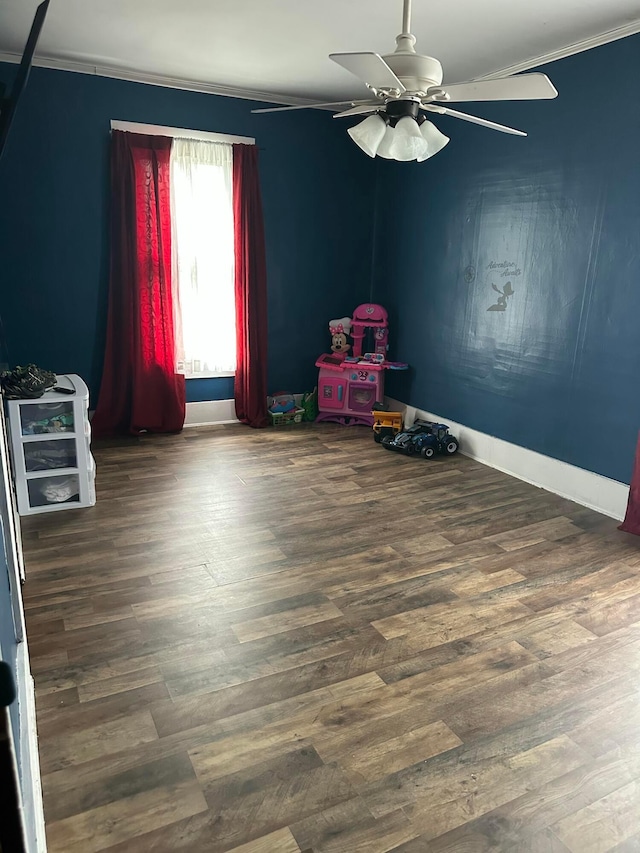 rec room with crown molding, wood finished floors, ceiling fan, and baseboards