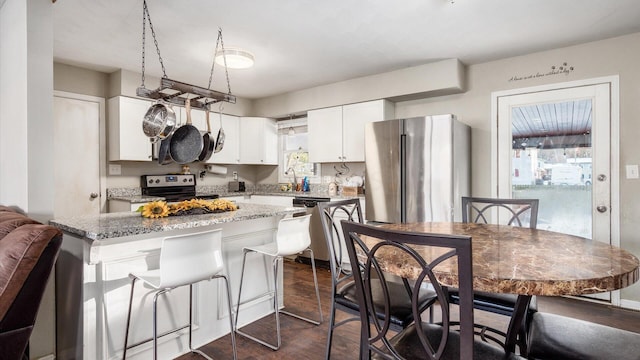 kitchen featuring light stone countertops, dark hardwood / wood-style flooring, white cabinets, and stainless steel appliances