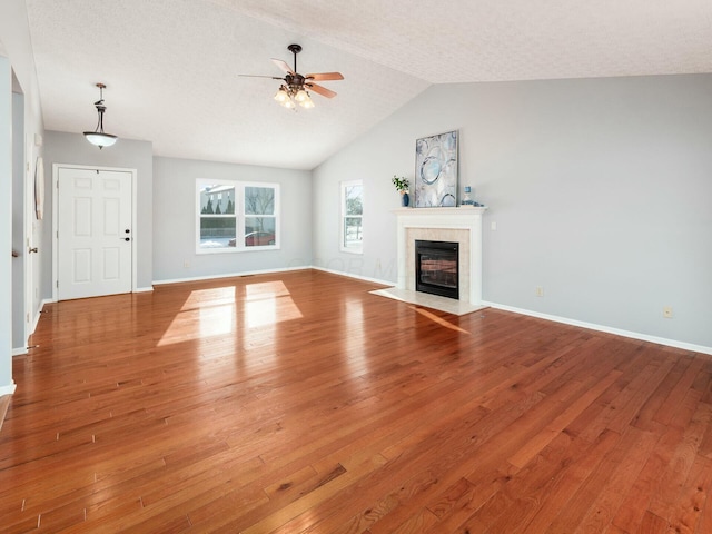 unfurnished living room featuring hardwood / wood-style floors, ceiling fan, lofted ceiling, and a fireplace