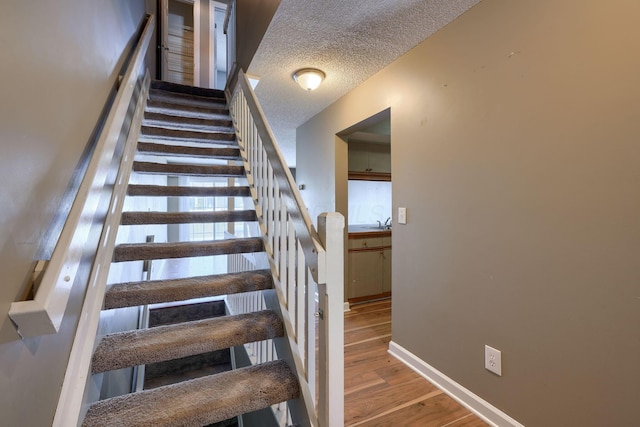 stairs featuring hardwood / wood-style floors and a textured ceiling