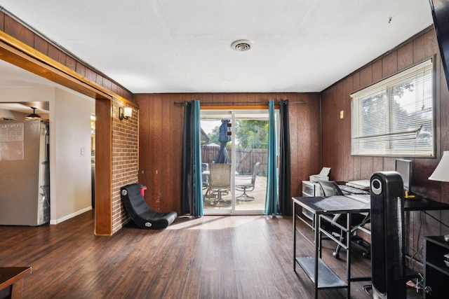 office space featuring ceiling fan, wood walls, and dark hardwood / wood-style flooring