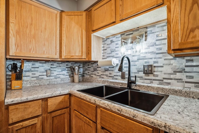 kitchen featuring backsplash, light stone countertops, and sink