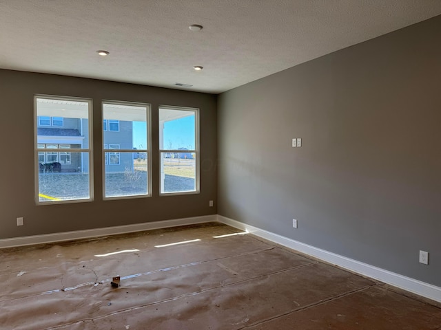 spare room featuring visible vents, baseboards, a textured ceiling, and concrete flooring