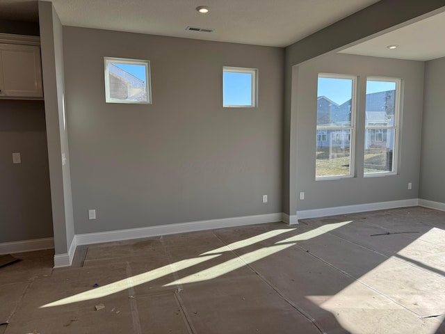 unfurnished room with visible vents, a healthy amount of sunlight, and baseboards