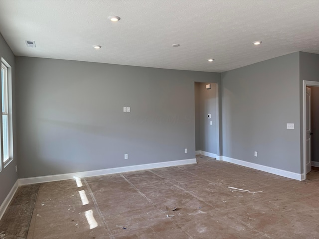 empty room featuring visible vents, baseboards, and a textured ceiling