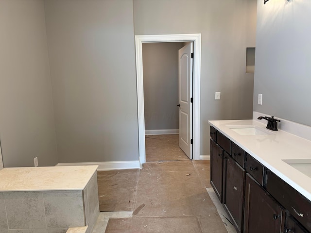 bathroom with double vanity, baseboards, and a sink