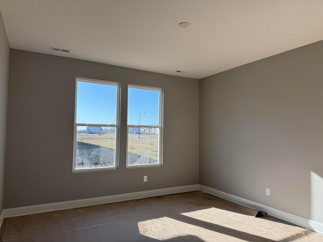 spare room with visible vents, concrete floors, and baseboards