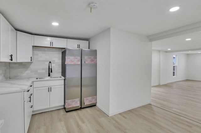 kitchen with tasteful backsplash, stainless steel refrigerator, sink, and white cabinets